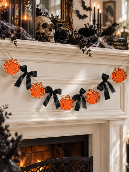 Pumpkin garland with black bows on a mantel with skulls and candles