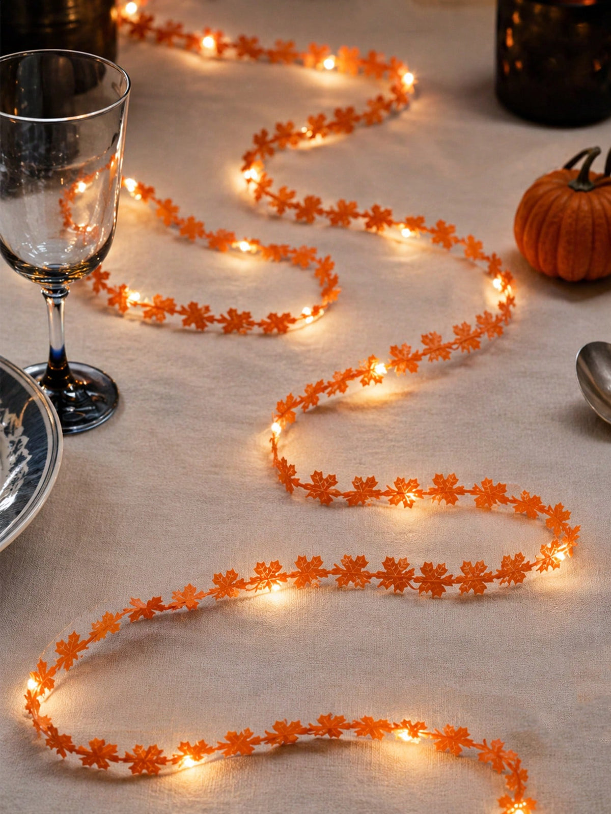 Maple leaf fairy string lights orange, winding on a tablecloth