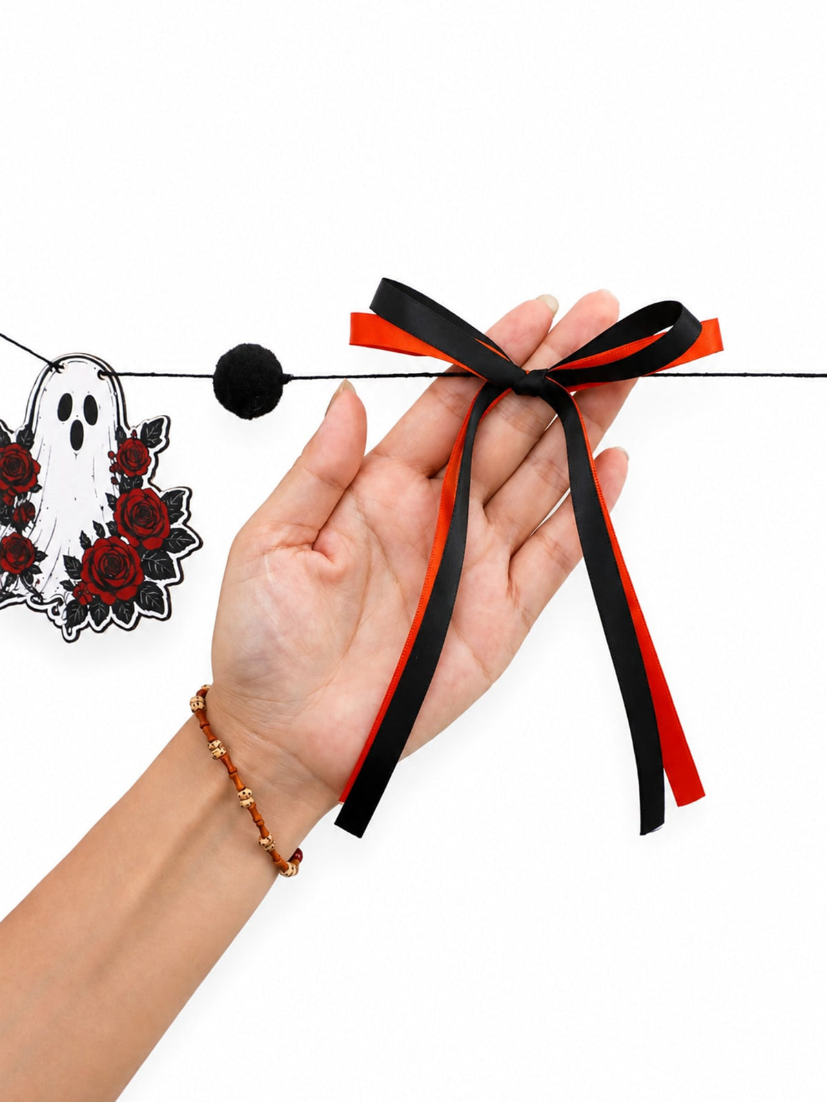 Gothic skull Halloween garland with roses black and orange ribbon bow held in hand