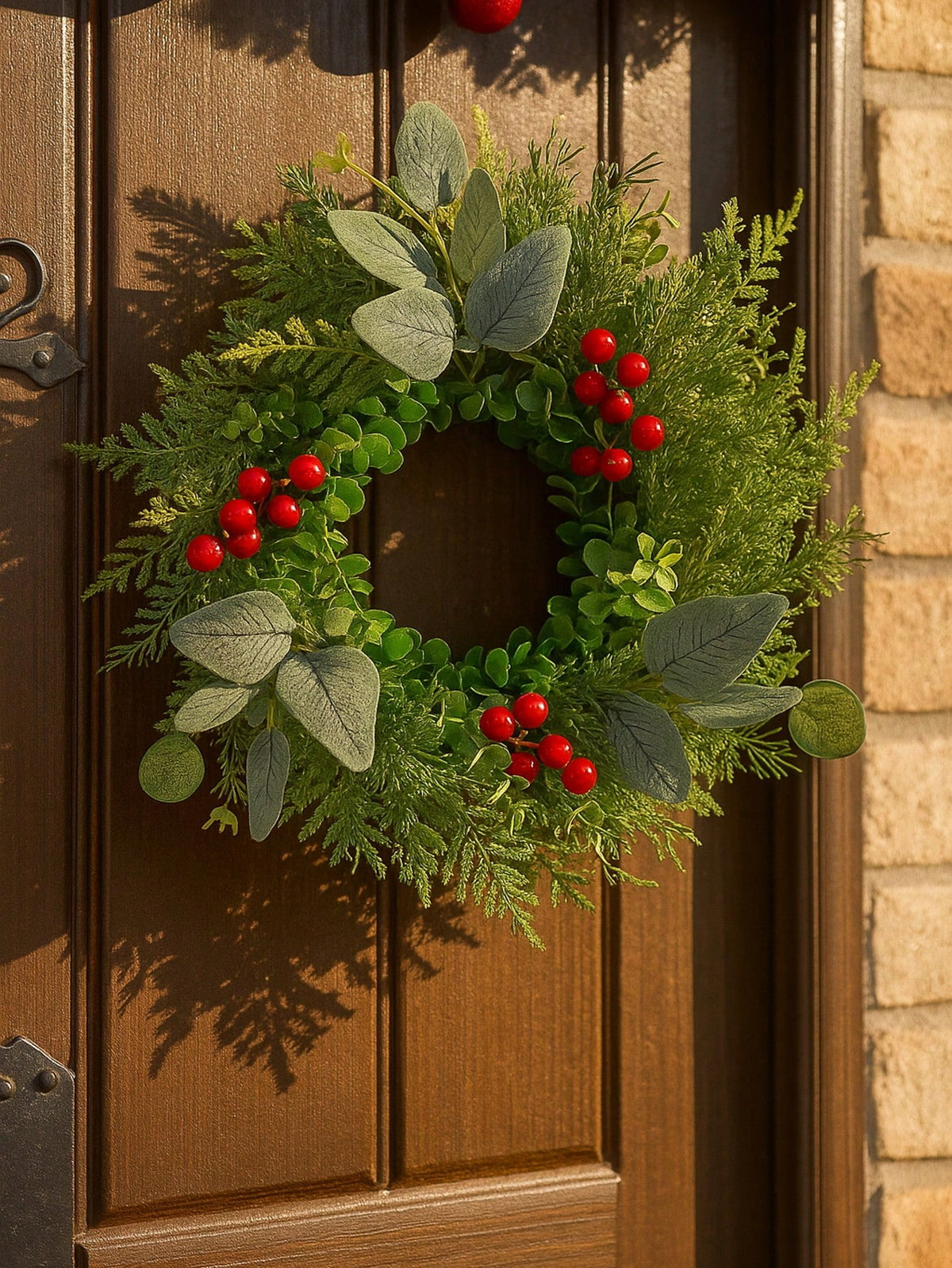 Eucalyptus and red berry Christmas wreath on a dark wood door