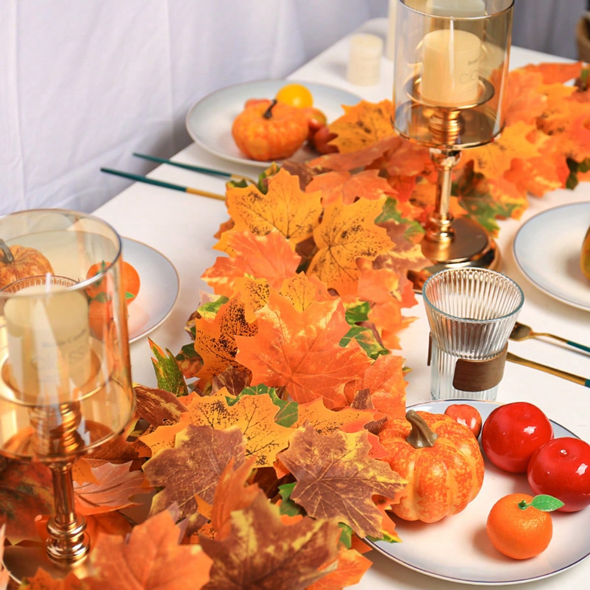 Artificial maple leaf garland on a table with candles