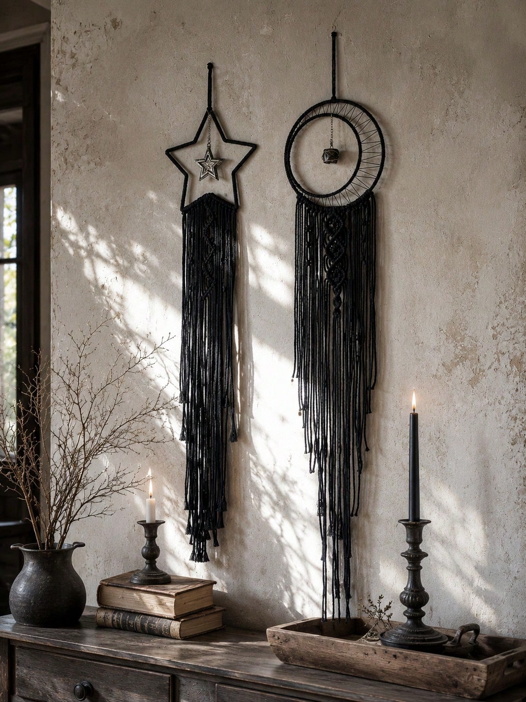 Black macrame moon dream catcher pair above a console with candles