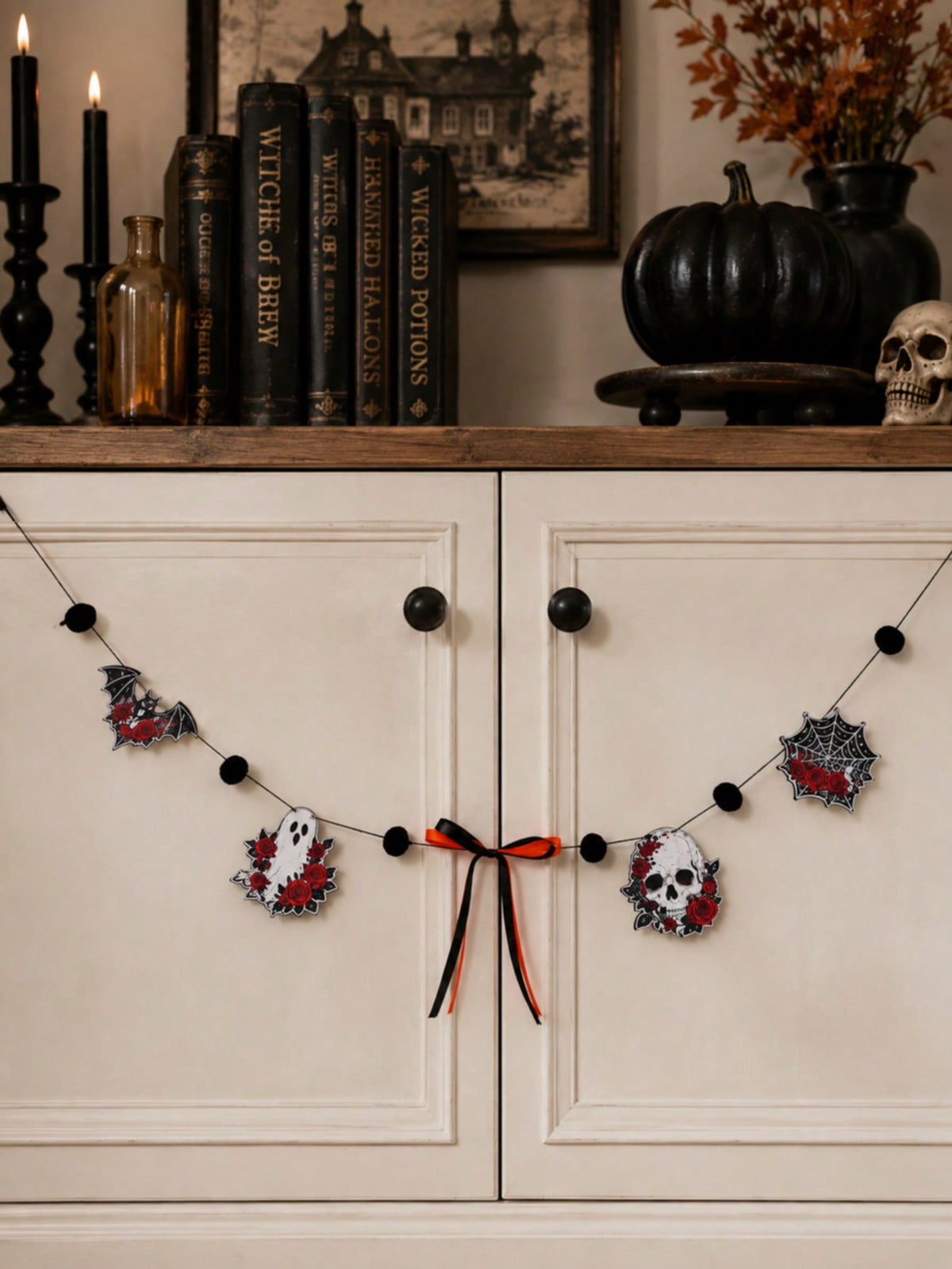 Gothic skull Halloween garland with roses across a white cabinet